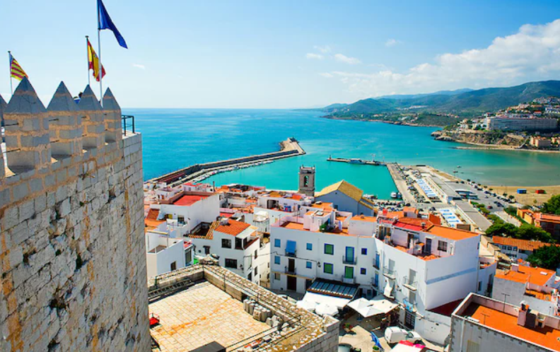 Whitewashed Peniscola rooftops and castle walls above a turquoise Mediterranean bay